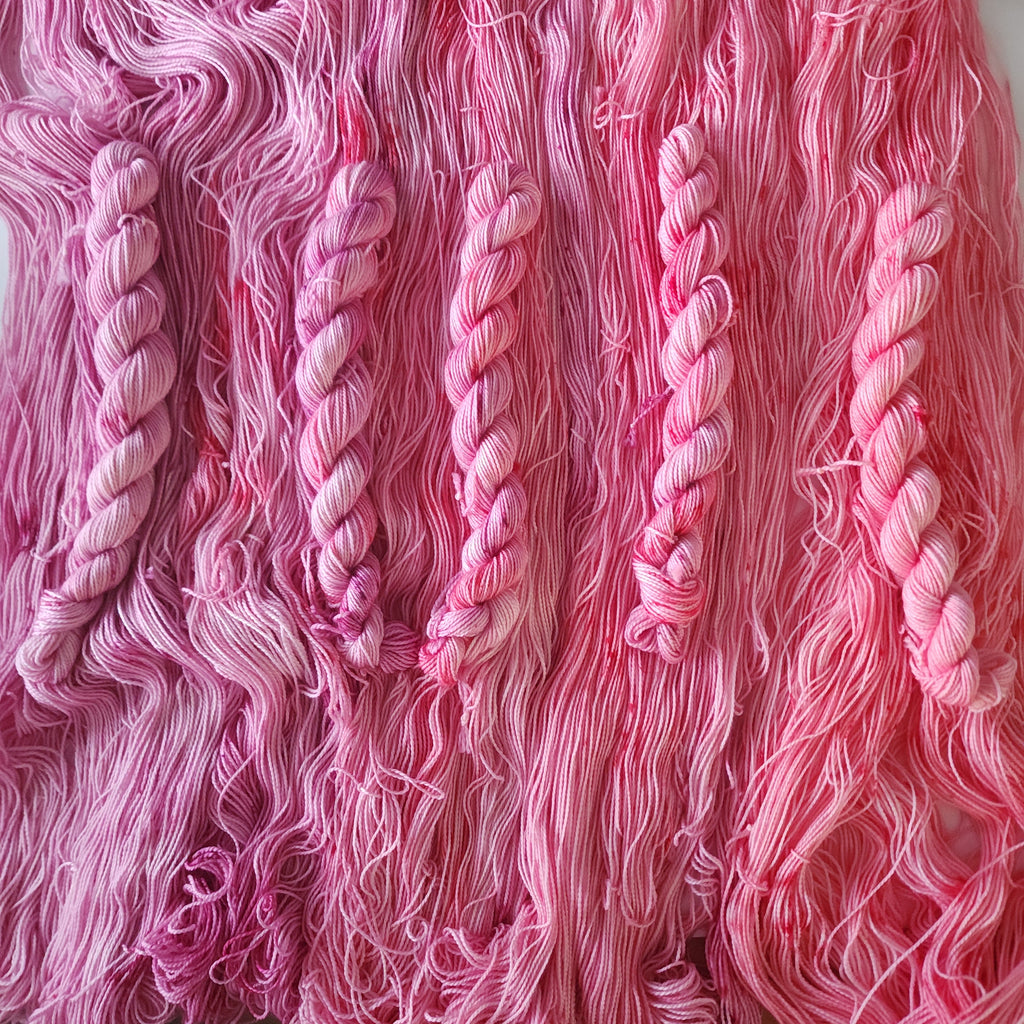 Close-up of pink yarn skeins with a focus on texture and color gradient.