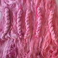 Close-up of pink yarn skeins with a focus on texture and color gradient.